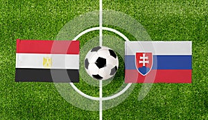 Pohľad zhora na futbalovú loptu s vlajkami Egypt vs. Slovensko na zelenom futbalovom ihrisku