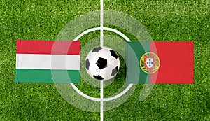 Top view soccer ball with Hungary vs. Portugal flags match on green football field