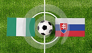 Pohľad zhora na futbalovú loptu s vlajkami Nigéria vs. Slovensko na zelenom futbalovom ihrisku