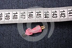 Top view of the soft tailor tape measure on a jeans material with a small figurine of a woman
