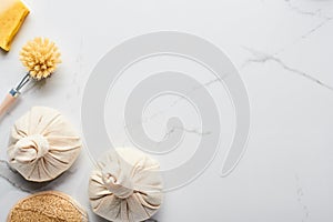 Top view of spa fabric sacs, bath sponge and body brushes on marble surface.