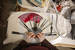 Top view of a Spanish woman& x27;s hands handcrafting a hand fan at the workshop