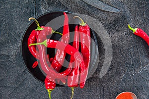 Top view Spicy ground red chili pepper on the black plate on the dark stone background. Selective focus. Space for text.