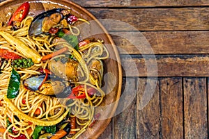 Top view of spicy spaghetti seafood on a wood plate on wood table