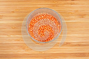 Top view of split red lentil in glassful on wooden surface