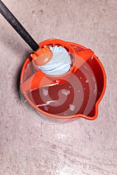 top view of squeezing mop in red bucket at home