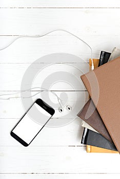 Top view of stack of book with phone and earphone