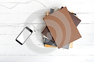 Top view of stack of book with phone and earphone