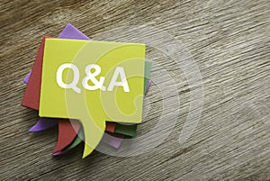 Top view stack of colorful speech bubbles with the top written with Q&A or questions and answers on wooden background