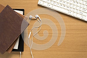 top view of stack of notebook with earphone and computer keyboard