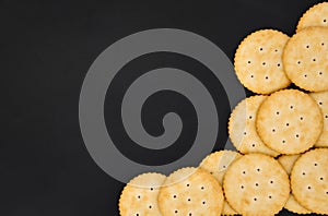 Top view stack of round cheese cracker cookies with sugar on black color background, copy space