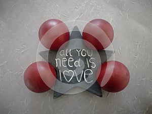 Top view of a star with a quote  all you need is love and four red balls on the floor