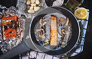 Top view steak salmon fillet in frying pan surrounding with olive oil, slice lemon, garlic, pepper, salted and ingredient