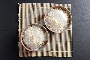Top view: steamed cooked basmati rice in round ceramic bowls over black stone photo
