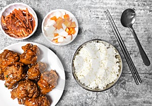 Top view steamed rice with Korean Spicy deep-fired chicken with side dish on the gray concrete table