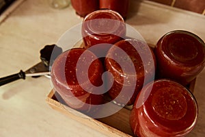 Top view with sterilized tins of freshly brewed tomato sauce, passata or juice upside down on a wooden crate. Canning