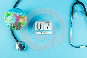 Top view Stethoscope Globe and 7th April calendar on blue background with copy space for text. Healthcare, life Insurance, world