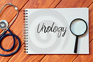 Top view of stethoscope,magnifying glass and notebook written with Urology on wooden background. photo