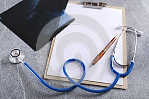 Top view of stethoscope,notebook, radiograph on the grey surface