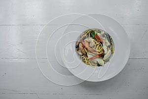 Top view of Stir-fried Spicy Spaghetti Seafood or `Spaghetti Pad Kee Mao`, Italian fusion food in Thai Style serve with white dish