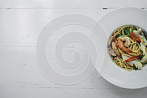 Top view of Stir-fried Spicy Spaghetti Seafood or `Spaghetti Pad Kee Mao`, Italian fusion food in Thai Style serve with white dish