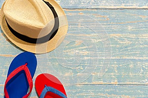 Top view of straw hat and flip flops on light blue wooden table. Summer beach holiday concept with copy space