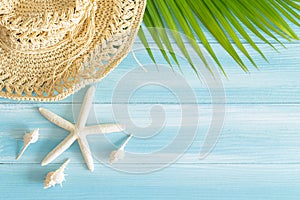 Top view of straw hat  ,leaves and  shells on the  a blue wooden background, Summer concept on empty blue wood floor