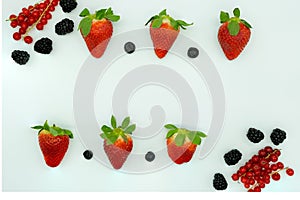 Top view of strawberries, blueberries, blackberries and currants placed in line with space in the center for text. Healthy food