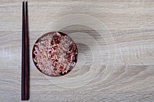 Top view stream brown rice in bowl and chopsticks on wooden back