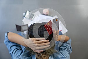 Top view of stressed young sitting Asian woman hands holding the head worry about find money to pay credit card debt and all loan