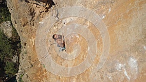 top view strong handsome man rock climber climbs up sunny limestone wall by challenging route. outdoor activity, active