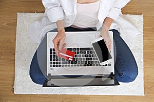 Top view of student girl surfing internet, online shopping on laptop and cellphone, holding debit / credit card, entering promo co