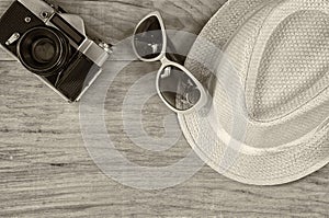 Top view of stylish hat woman sunglasses old camera over wooden table. black and white photo. vacation and travel concept