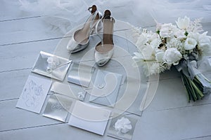 top view of stylish wedding invitations with bridal shoes and bouquet