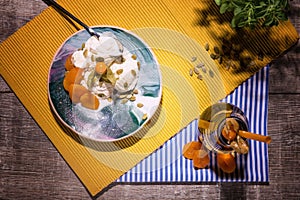 Top view of a summer dessert. Vanilla ice cream and jar of apricot juice on a wooden background. Creamy organic snacks.