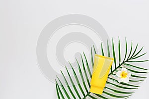 Top view of suncream, plumeria flower palm leaf. spf cream on white background with copy space. Directly above. Bright summer,