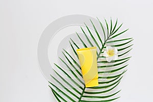 Top view of suncream, plumeria flower palm leaf. spf cream on white background with copy space. Directly above. Bright summer,