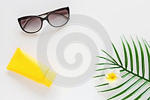 Top view of suncream, straw hat, palm leaf, sunglasses. spf cream on white background with copy space. Directly above. Bright