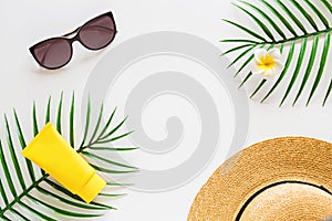 Top view of suncream, straw hat, palm leaf, sunglasses. spf cream on white background with copy space. Directly above. Bright