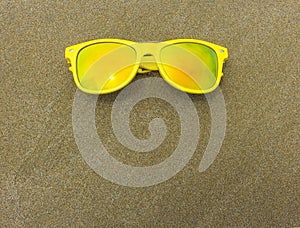 Top view of sunglasses on the beach near the blue sea with sand. Background with copy space.