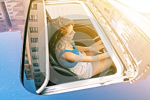 Top view from sunroof of a young beautiful woman sitting on car seat and drive carefuly.