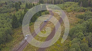 Top view of SUVs driving on country road. Clip. Off-road racing on mud roads in rural forest area