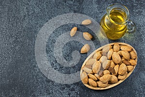 Top view Sweet Almond oil in glass of bottle on dark grey table