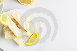 Top view of sweet and yummy dessert. Waffles with milk and lemon filling. Tasty food. Lemon slices. Wafers on each other on plate