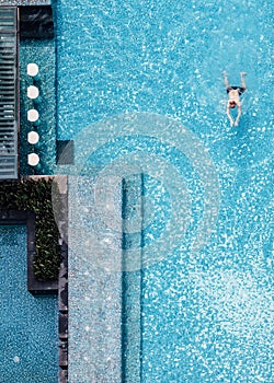 Top view of swimming pool with floating bar and a man swimming in summer