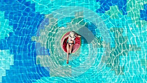Top view of the swimming pool with a lady in a swim ring. Summer vacation concept.