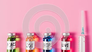 top view of syringe and bottles with love hope joy and peace vaccine signs in row