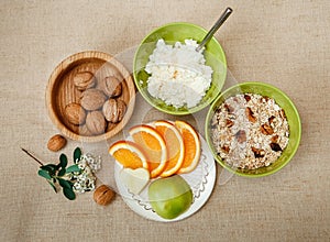 Top View.Table Appointments for Healthy Organic Breakfast.Walnuts,Oatmeal and Cottage Cheese.Cut Orange and Apple.Green Ceramic