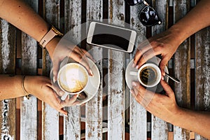 Top view of table with coffee and friends couple enjoying drinks and break - females caucasian hands and phone and sunlgasses on
