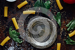 Top view of table with italian tortiglioni pasta, metal plate and spices.